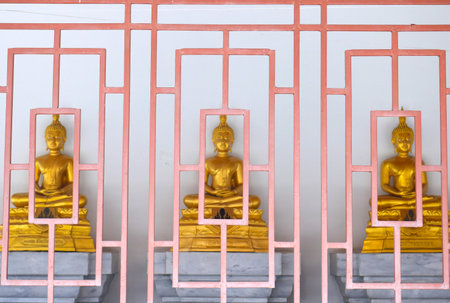 Golden Buddha statues with orange fence in Thai templeの写真素材