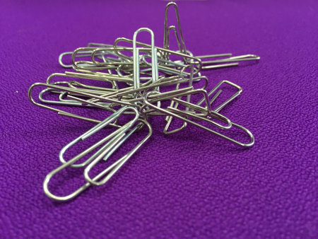 Image of silver paper clip isolated on purple background