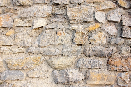 Wall of stones and cement in gray tones with an orange stone in a strong point.の写真素材