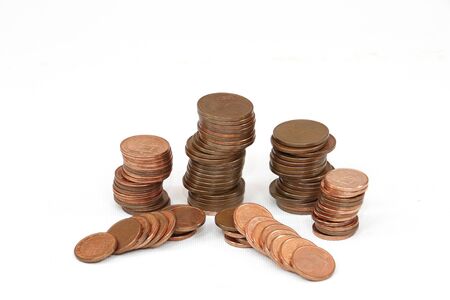 Copper coins of little value stacked on a white backgroundの写真素材
