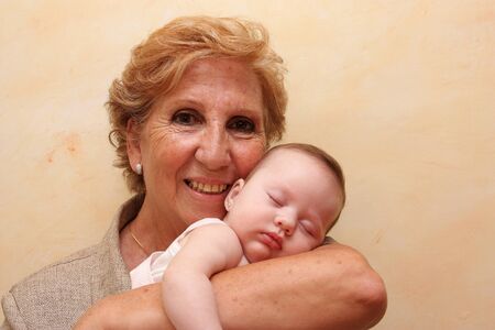 Close up of a grandmother with her ??granddaughter in her arms.の写真素材