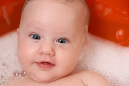 Beautiful baby blue eyes taking a relaxing bubble bath