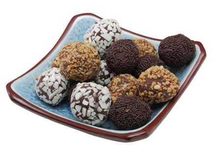 Chocolate bonbons with various aspects presented in a blue bowl on a white backgroundの写真素材