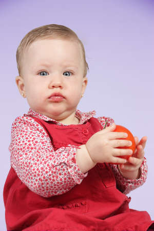Portrait of a girl with red dress and  a tomato in the handsの写真素材