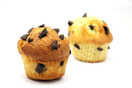 Two cupcakes with chocolate chips embedded on a white backgroundの写真素材
