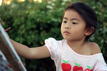 Portrait of little girl painting, summer outdoorの写真素材