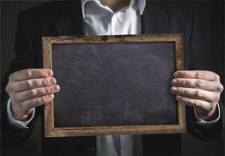 Businessman holding in hand an empty blackboard with frameの写真素材