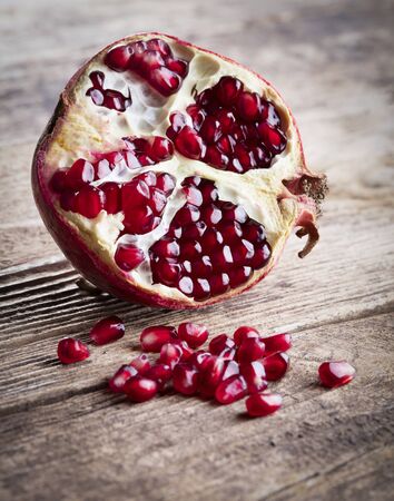 Half of a ripe pomegranate on a wooden backgroundの写真素材