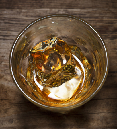 single glass of alcohol drink whiskey with ice on wooden backgroundの写真素材
