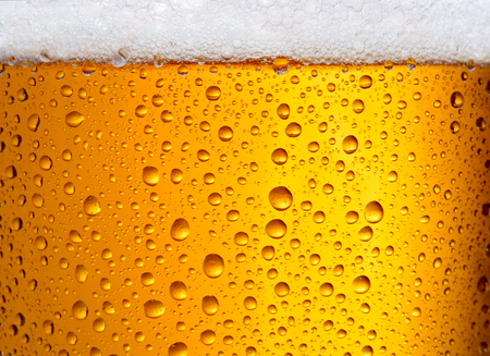 close-up view of glass with beer with droplets as textured backgroundの写真素材