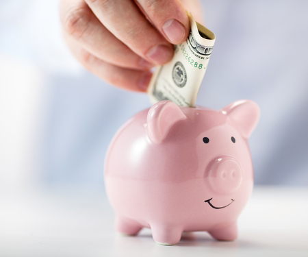 pink ceramic piggy bank with hand putting money insideの写真素材