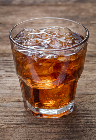 single glass of cola with lot of crashed ice on wooden backgroundの写真素材