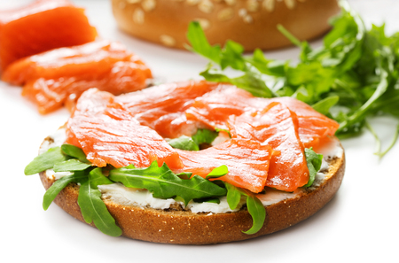 single fresh bagel sandwich with salmon, arugula and cream cheese isolated on white backgroundの写真素材