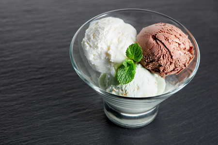 three balls of ice cream in glass on black slate backgroundの写真素材