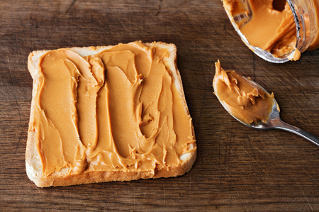 peanut butter sandwich with spoon and jar on wooden backgroundの写真素材