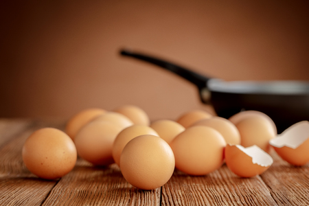 pile of chicken eggs with pan on wooden tableの写真素材
