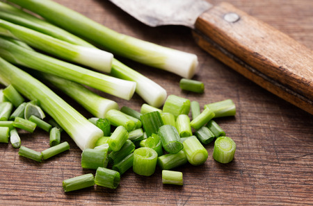heap of green onion with knife on wooden backgroundの写真素材