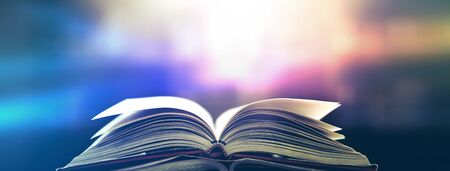 Imagine a picture book of an ancient book opened on a wooden table with a sparkling golden background. With magical power, magic, lightning around a glowing glowing book In the room of darknessの写真素材
