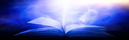 The blurred book that is bewitched with magic, the magic light in the dark, with the bright light shining down as the power to search for knowledge. For research and use as a blurred backgroundの写真素材