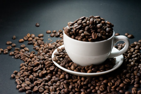 coffee in white cup and coffee beans are the background.