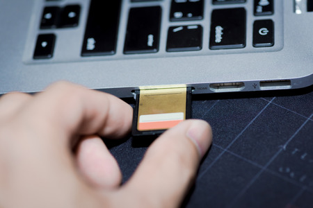 inserting sd card memory drive plugged into a computer laptop port.の写真素材