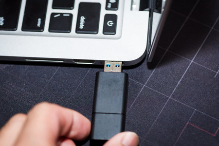 Hand inserting USB flash memory drive plugged into a computer laptop port.