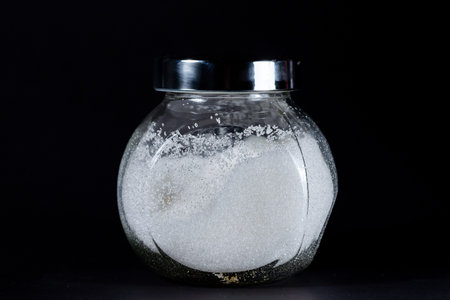 Close up of crystal sugar in a jar on black background.の写真素材