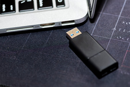 Hand inserting Flash drive memory drive plugged into a computer laptop port.