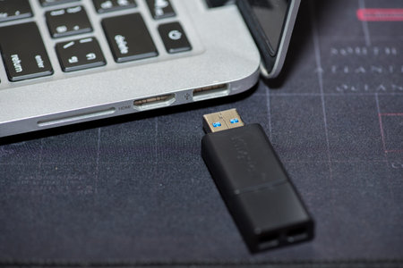 Close-up of a USB flash drive placed near a laptopの写真素材