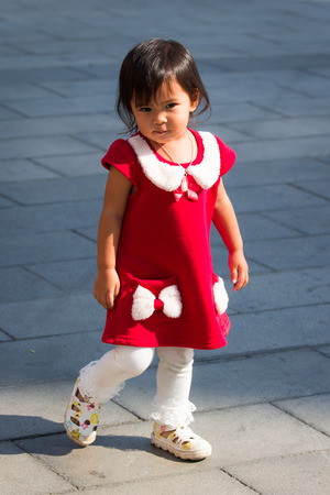 Cute little girl is walking on the groundの写真素材