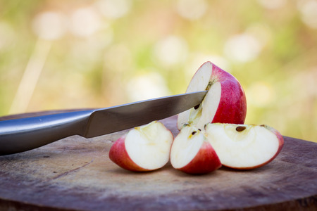 Knife slice apple on wooden block over meadow backgroundの写真素材