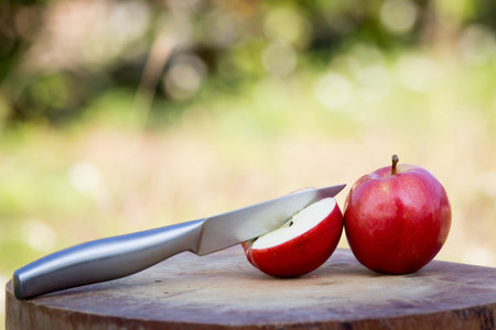 Knife slice apple on wooden block over meadow backgroundの写真素材