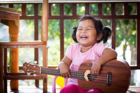 Cute little girl is playing ukuleleの写真素材