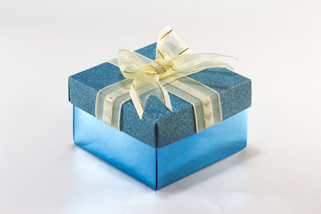 Blue gift box with gold ribbon and bow on white backgroundの写真素材