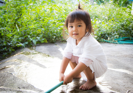 Cute little girl is washing her hand with rubber tubeの写真素材