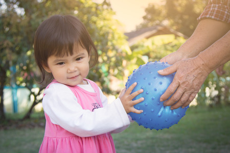 Cute little girl carry ball from old woman in soft styleの写真素材