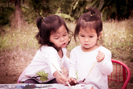 Cute little girls are painting with watercolor together in vintage styleの写真素材