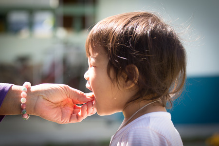 Old woman's hand feeding cute little girlの写真素材
