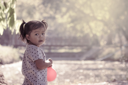 Cute little girl is playing in the park in vintage styleの写真素材