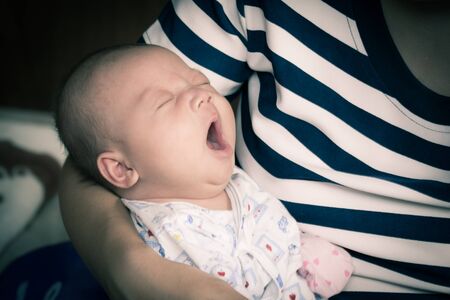 new born baby boy sleeping, yawning on mother's arm in vintage styleの写真素材