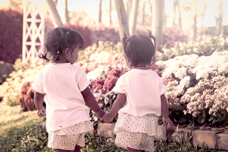 Cute little girl walking and holding hand together in flower garden in vintage styleの写真素材