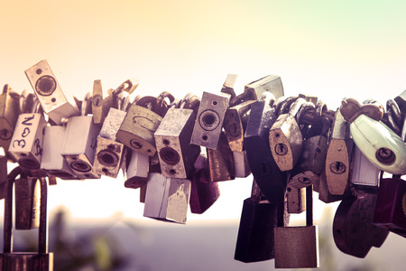 Old rusty padlocks hanging on bridge railing in vintage color styleの写真素材