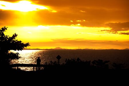 man is taking a photo beautiful sunset over the seaの写真素材