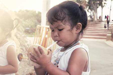 little girl drinking coconut juice in summer timeの写真素材