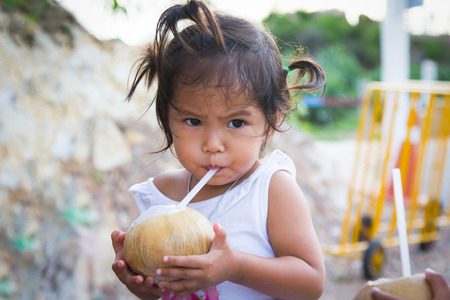 little girl drinking coconut juice in summer timeの写真素材