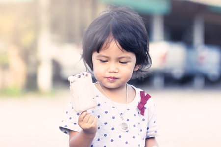 Cute little girl is eating icecream,soft color filterの写真素材