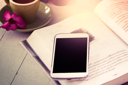 smart phone,cellphone on open book with cup of coffee in vintage color filterの写真素材