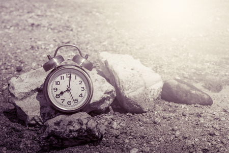 retro clock on rock in sand lake in vintage color toneの写真素材