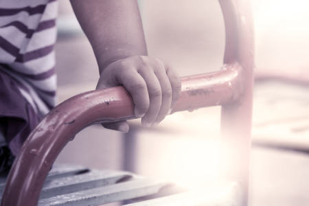 kid hand holding  handlebar steel in playground,vintage filterの写真素材