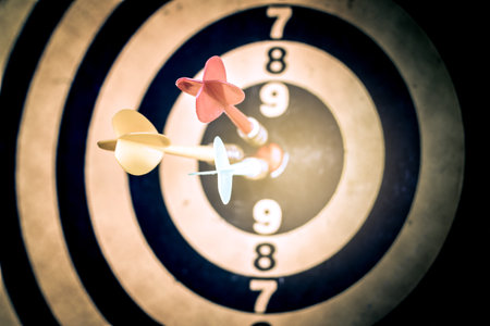 Success hitting target aim goal achievement. Three darts in target center on dartboard, vintage effect filterの写真素材